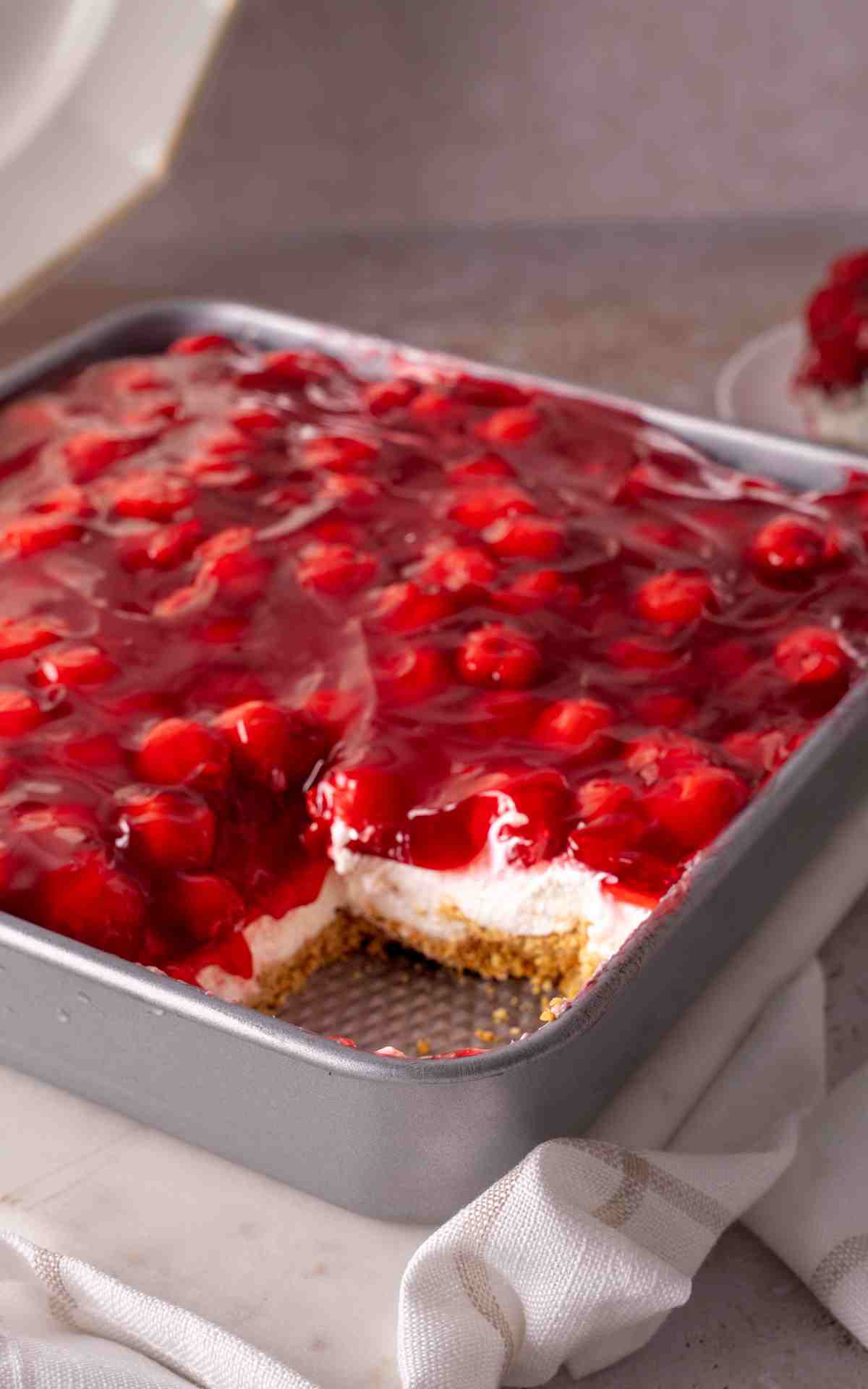 Layers of no bake cherry dessert inside a square pan.