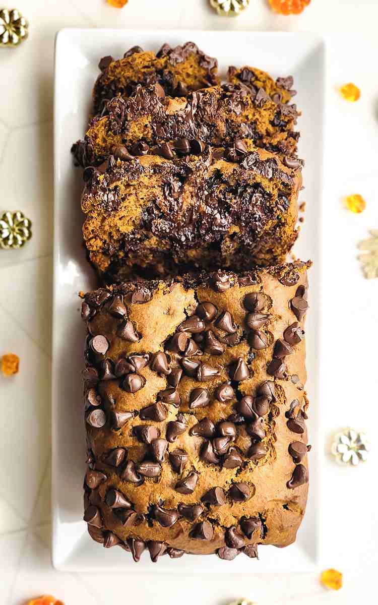 Top view of a half sliced loaf of pumpkin loaf bread with chocolate chips.