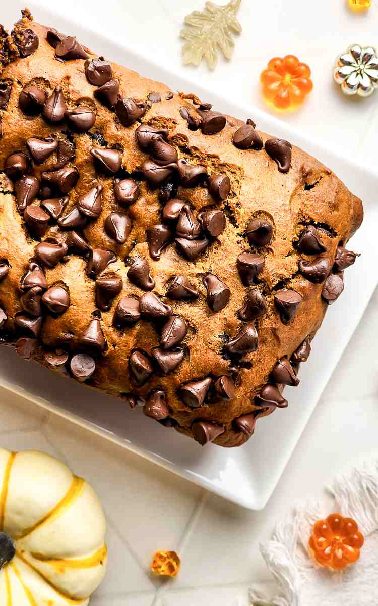 Uncut pumpkin and chocolate chip bread on ceramic rectangular dish.