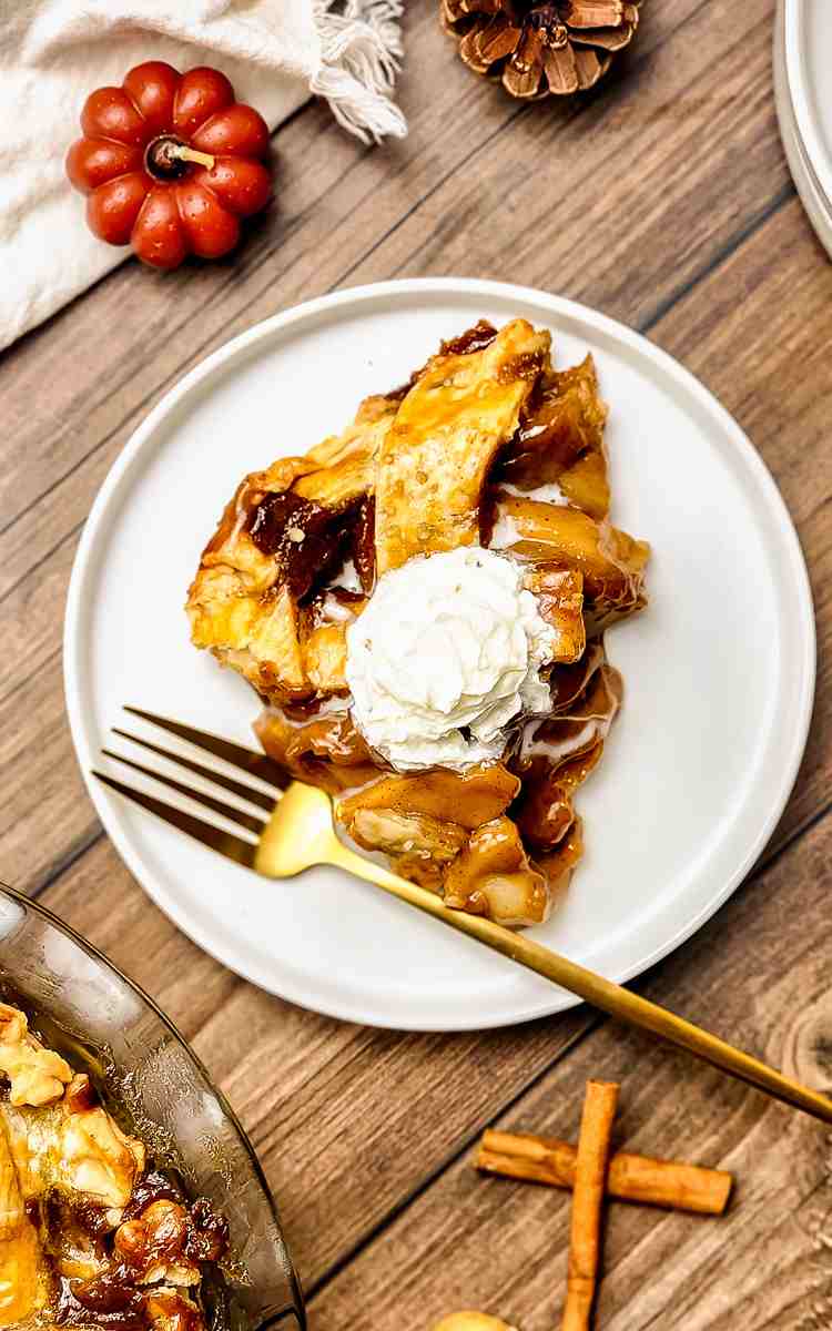 A slice of homemade apple pie topped with whipped cream.