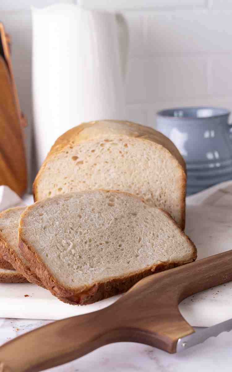 Bread machine white bread with slices next to bread knife.