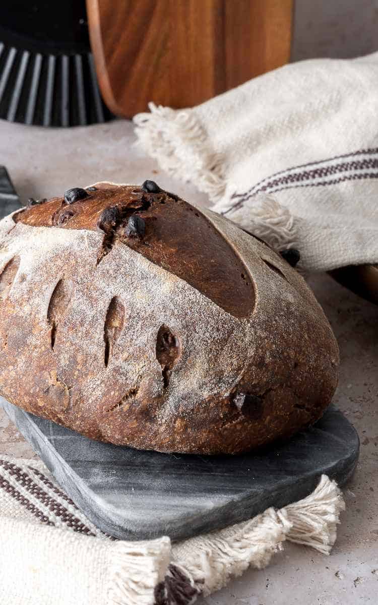 Chocolate sourdough batard on marble tray.