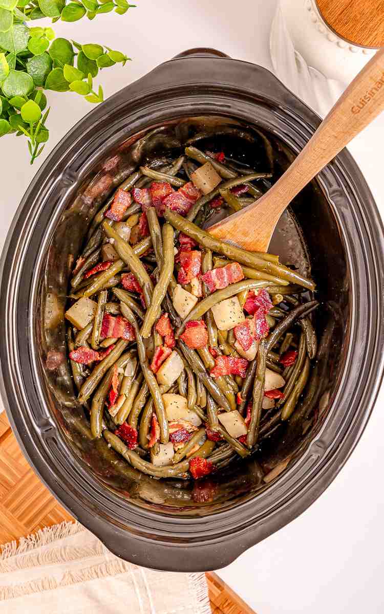 Fresh green beans and potatoes cooking in a slow cooker.