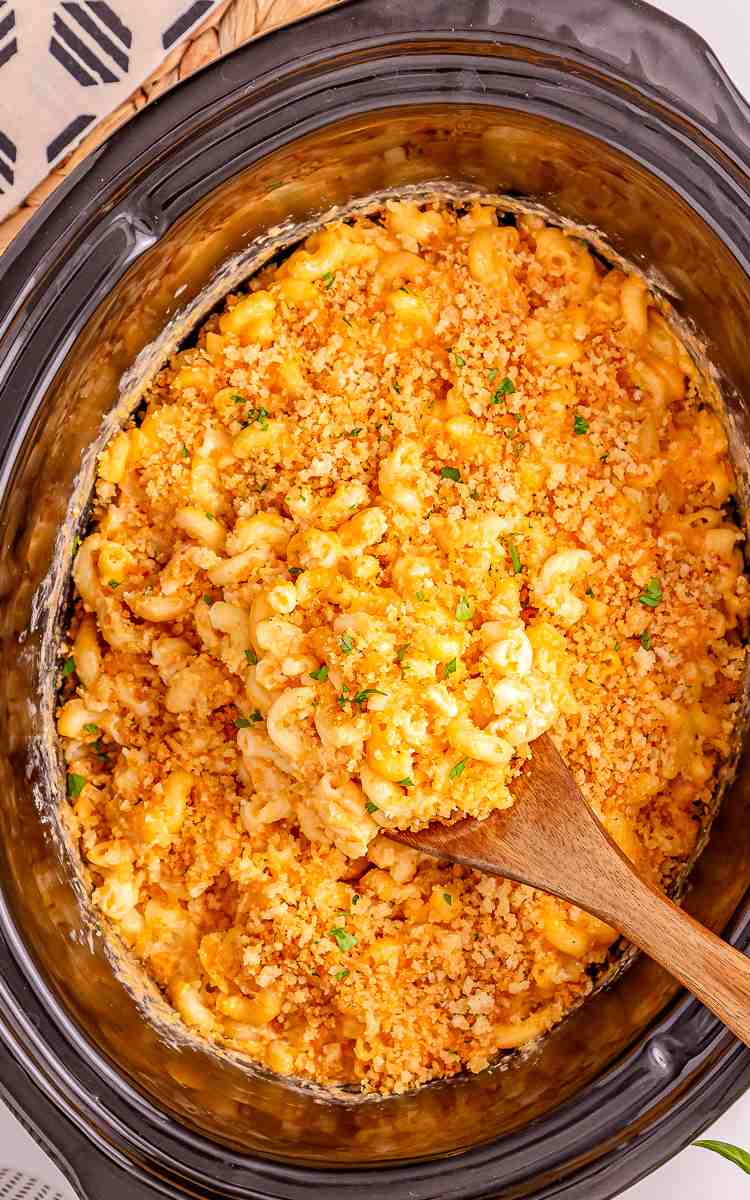 Melty crockpot mac and cheese with a serving spoon in the crockpot.