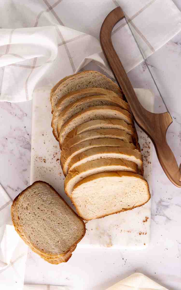 Sliced homemade sandwich bread with bread knife.