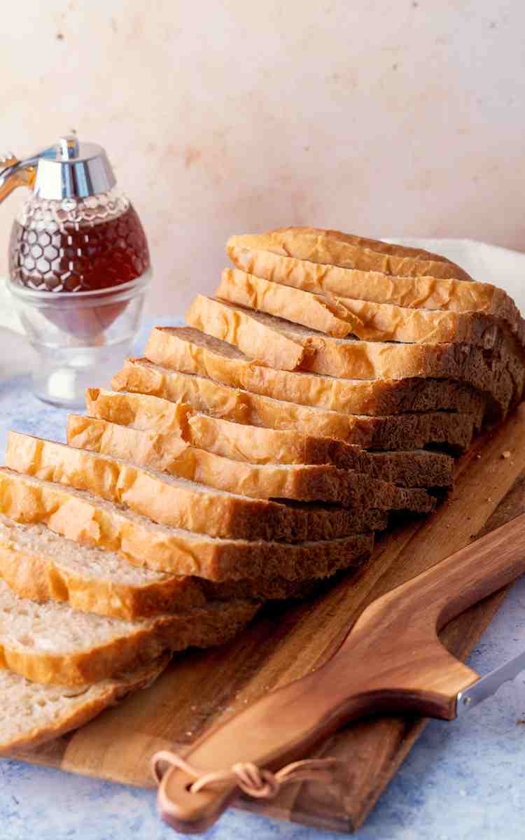 Slices of white bread with honey on cutting board.