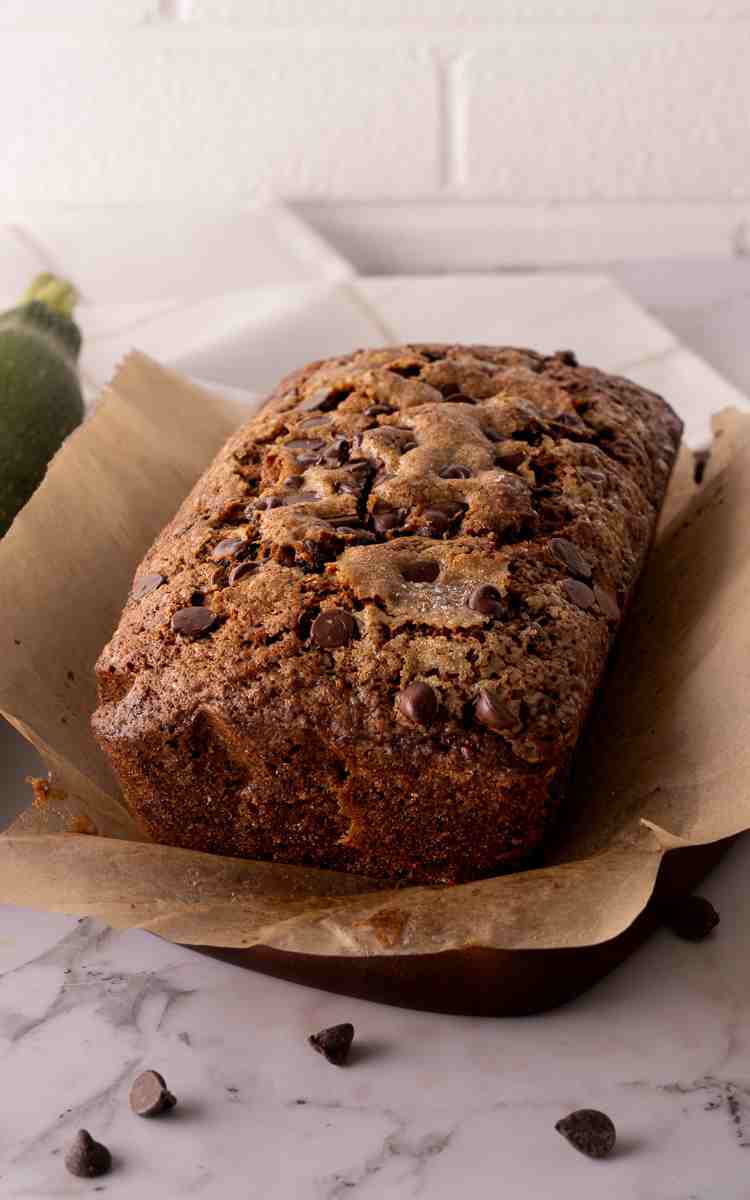 Unsliced chocolate chip zucchini bread on parchment paper.