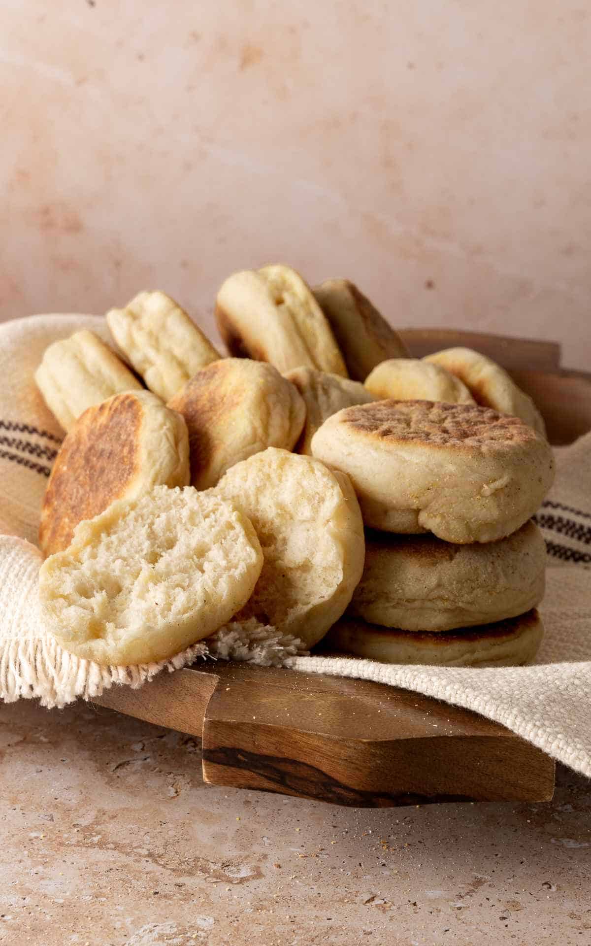 Freshly made Sourdough discard English muffins on linen in wooden bowl.